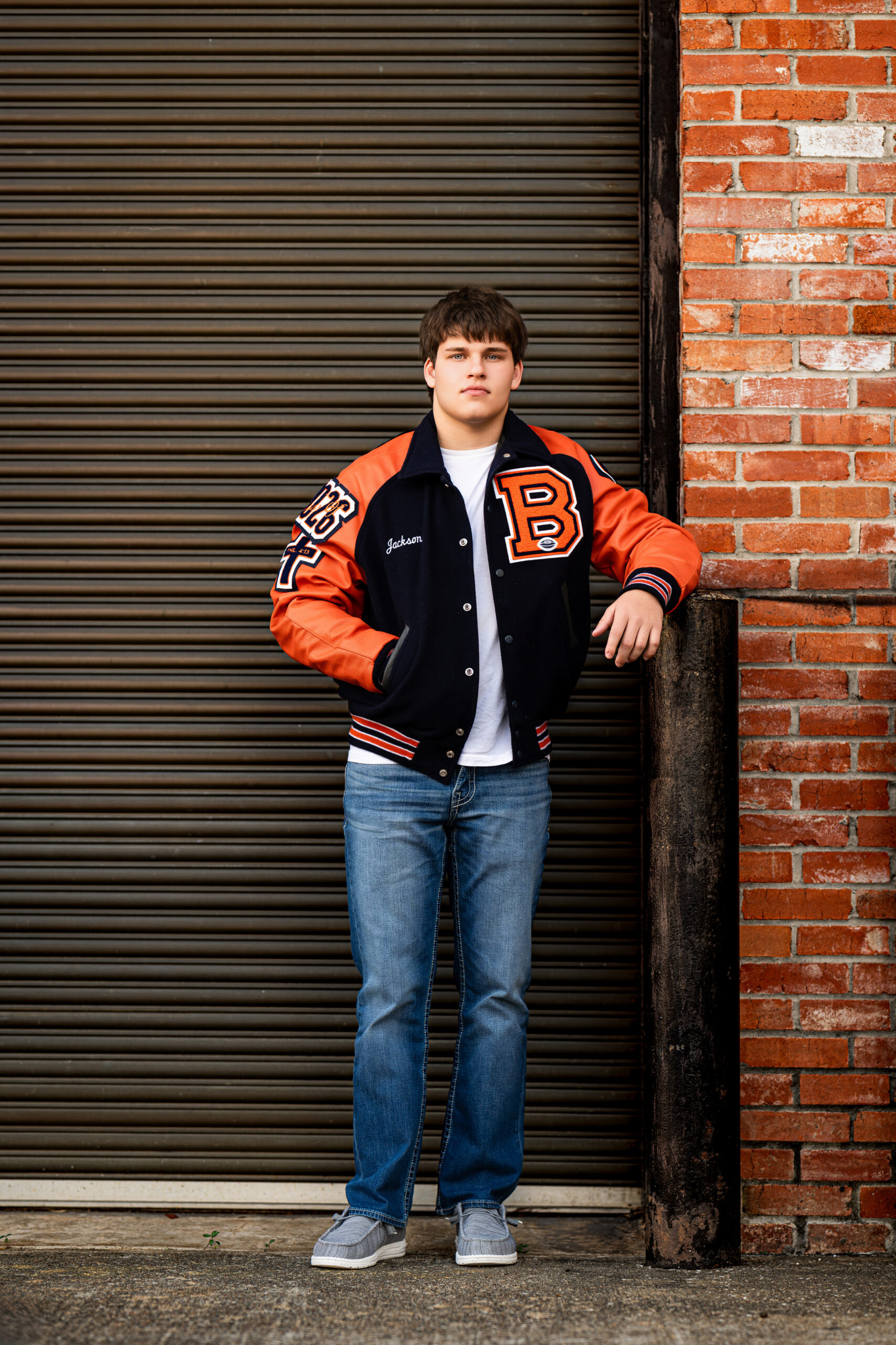 A picture of a senior high school student standing in front of a steel door / brick wall in Conroe, Texas.