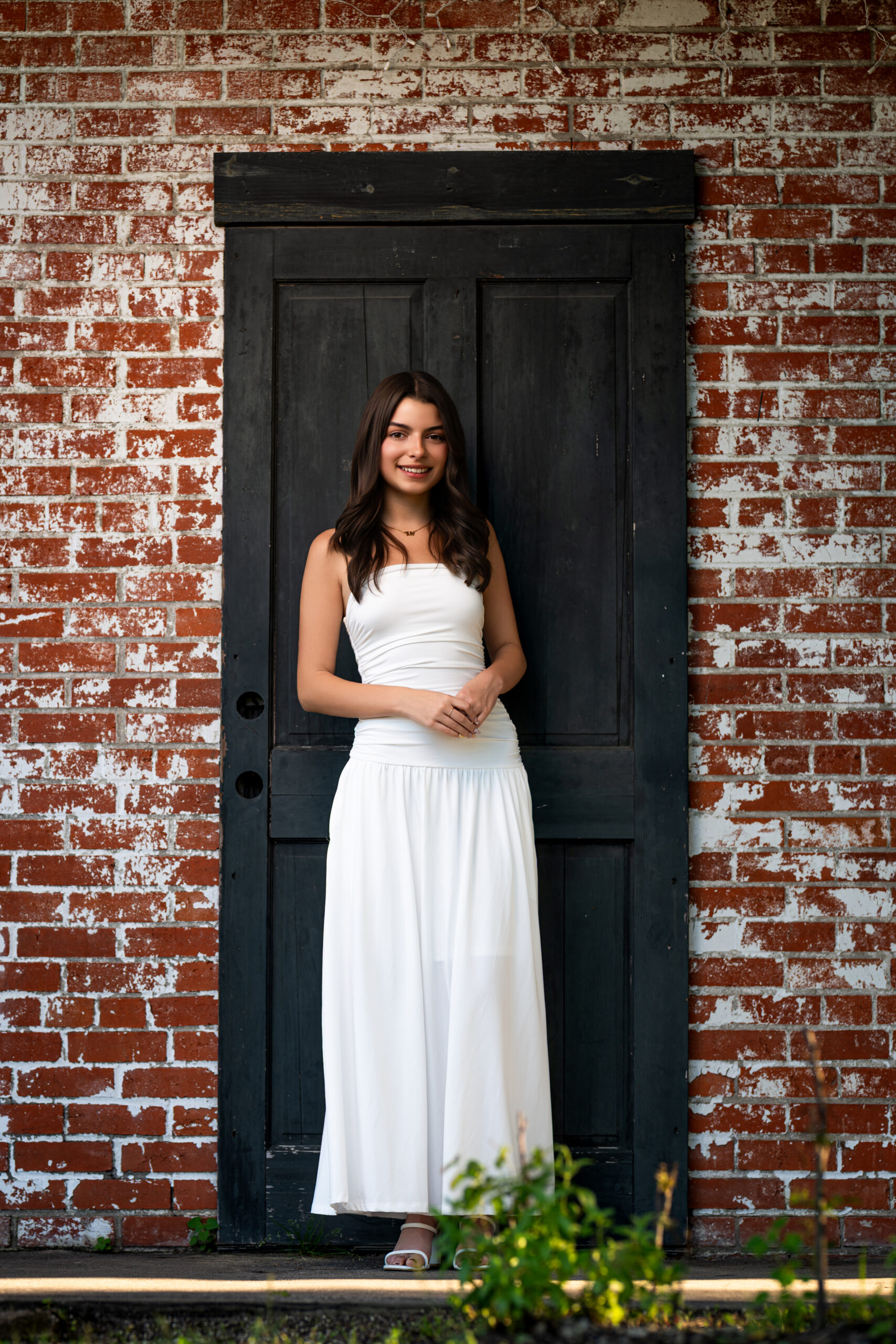 Picture of a high school senior standing in front of an old rustic brown door near Mont Belvieu, Texas.