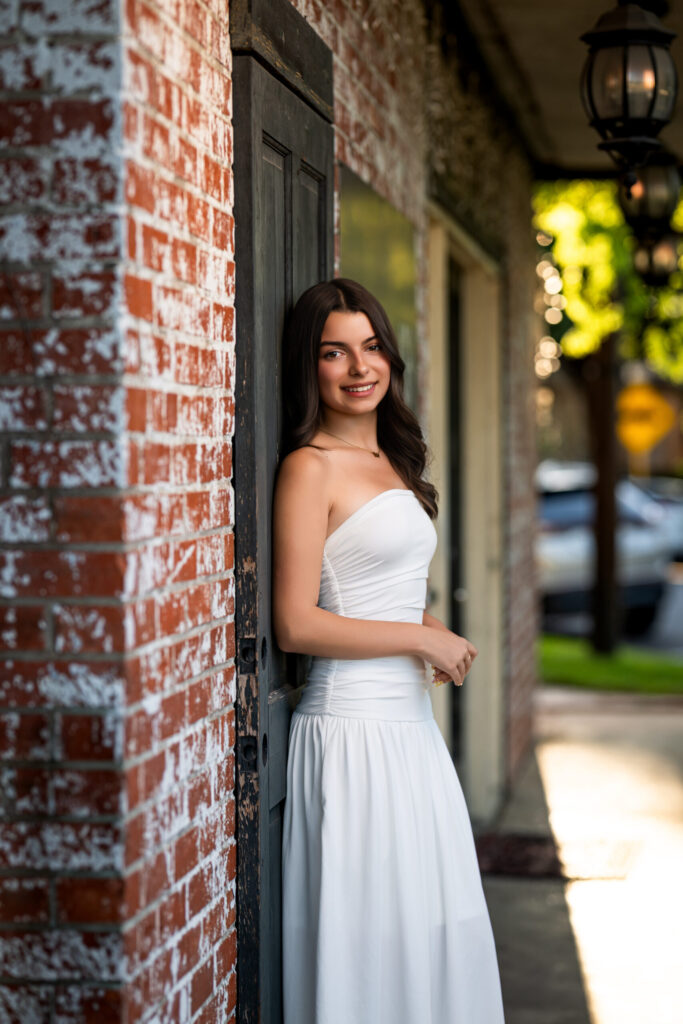 Picture of a high school senior posing against an old brick wall in Old Town Spring, Texas.