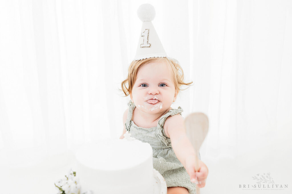 A picture of a one year girl posing for her studio cake smash photo session in The Woodlands, Texas.