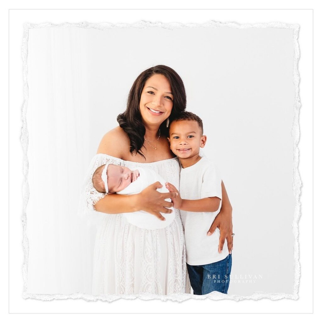 Picture of a mom, son and new baby sister posing for a studio portrait in The Woodlands, Texas.