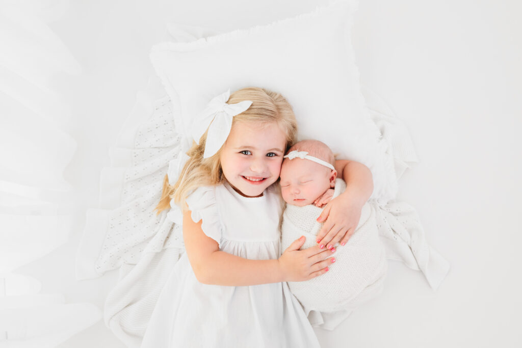A picture of a newborn baby with her sister during a studio photo session in The Woodlands, Texas.