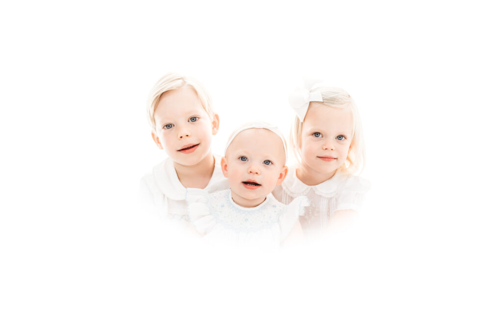 A picture of three siblings posing for their heirloom portraits in a studio located in The Woodlands, Texas.