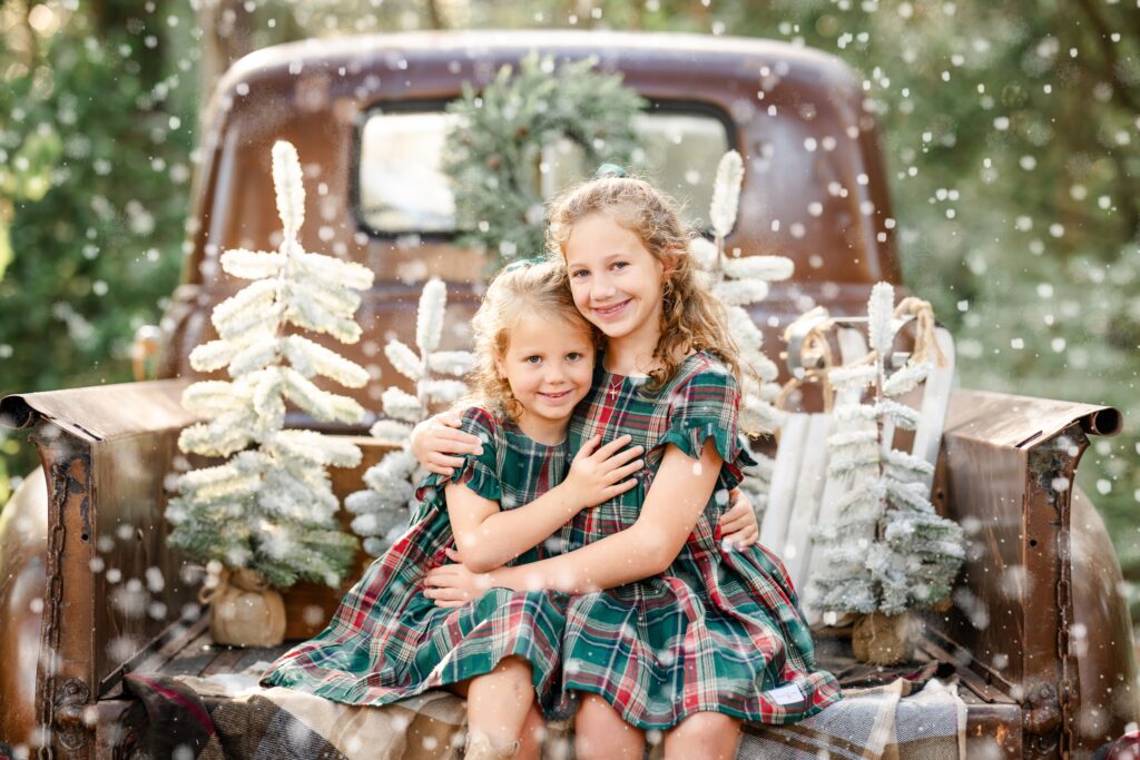 A picture of two you girls posing in a forest setting for their Christmas mini photos in The Woodlands, Texas.