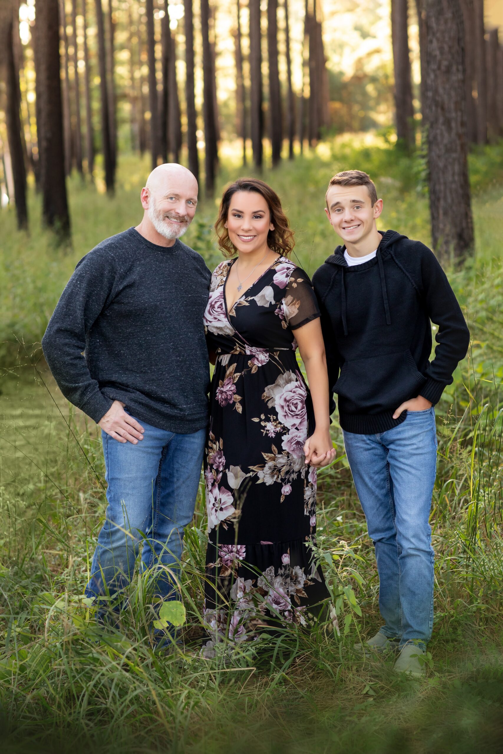 The Woodlands family photographer Bri Sullivan on a portrait session with her family in a Texas pine forest, featuring a floral dress and casual wear.